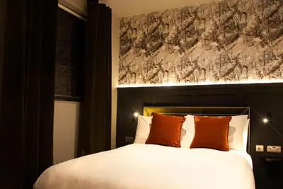 a bedroom with a large bed with orange pillows at The Coachman Hotel in Kilsyth