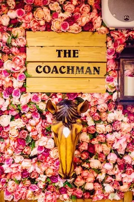 a sign with a cow on a wall with flowers at The Coachman Hotel in Kilsyth