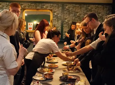 a group of people standing around a table eating food at The Coachman Hotel in Kilsyth