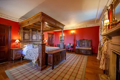 a bedroom with a canopy bed and red walls at Barcaldine Castle in Oban