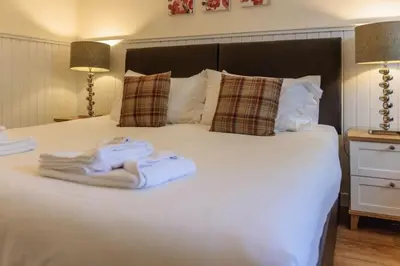a white bed with a pile of towels on it at Shore House in Tarbet