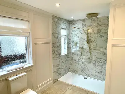a bathroom with a shower with a stone wall at Shore House in Tarbet
