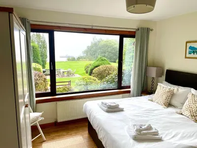 a bedroom with a bed and a large window at Shore House in Tarbet