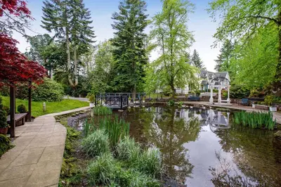 a pond in a garden with a house in the background at Wyndham Duchally Country Estate in Auchterarder
