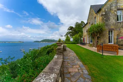 a house with a stone wall next to the water at Dungallan Country House in Oban