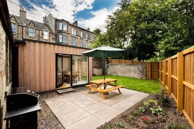 a patio with a wooden table and an umbrella at Trinity Lodge - Home with Private Garden and Parking in Edinburgh