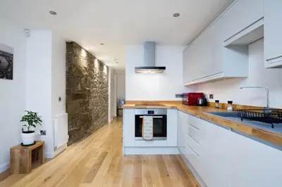 a kitchen with white cabinets and a wooden floor at Trinity Lodge - Home with Private Garden and Parking in Edinburgh