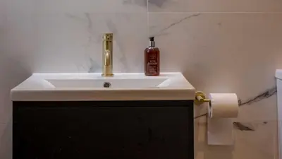 a bathroom sink with a bottle of alcohol sitting on it at Brisbane House Hotel in Largs