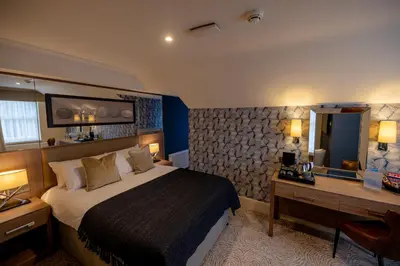 a hotel room with a large bed and a desk at Brisbane House Hotel in Largs
