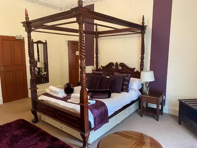 a bedroom with a wooden canopy bed with a table at Avonbridge Hotel in Hamilton