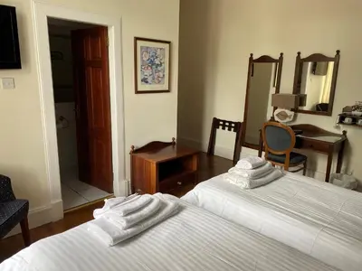a bedroom with two beds and a table and a desk at Avonbridge Hotel in Hamilton