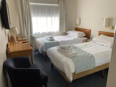 a hotel room with two beds and a chair at Avonbridge Hotel in Hamilton
