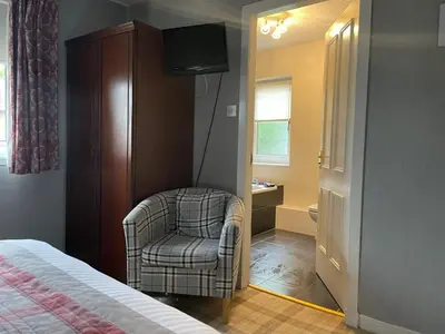 a bedroom with a chair and a television in it at Gowanlea Guest House in Balloch