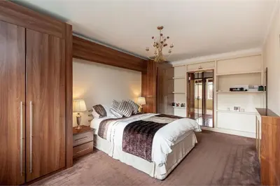 a bedroom with a large bed and a dresser at Hillhouse in Edinburgh