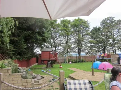 a woman standing under an umbrella in a park with a playground at Three Bridges Bed & Breakfast in Rosyth