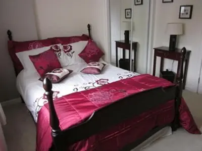 a bedroom with a bed with pink sheets and pillows at Three Bridges Bed & Breakfast in Rosyth