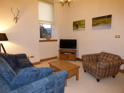 a living room with a couch and a chair and a tv at The Pipers No 7 Lomond Castle in Balloch