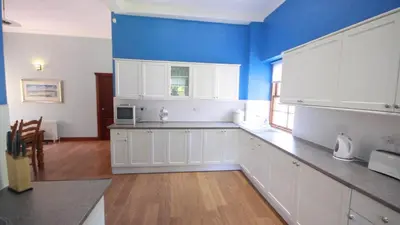 a large kitchen with white cabinets and a blue wall at Coachouse in Balloch