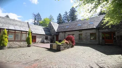 a large stone house with a brick driveway at Coachouse in Balloch
