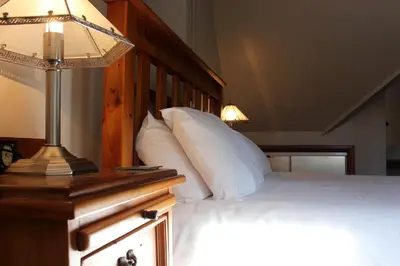 a bedroom with a bed and a lamp on a table at Stables Lodge in Balloch