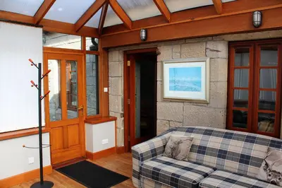 a living room with a couch and a stone wall at Smiddy Lodge in Balloch