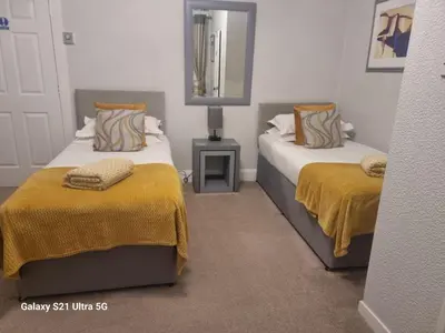 a bedroom with two beds with yellow blankets and a mirror at St Leonards Guest House in Largs