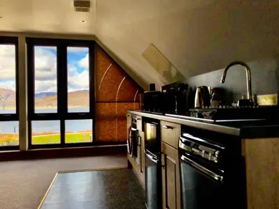 a kitchen with a sink and a stove and windows at Hunters Lodge Apartments in Ballachulish