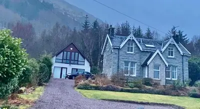 a large house with a car parked in front of it at Hunters Lodge Apartments in Ballachulish