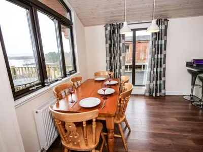a dining room with a table and chairs and windows at Chalet Loch Leven Lodge by Interhome in Ballingry