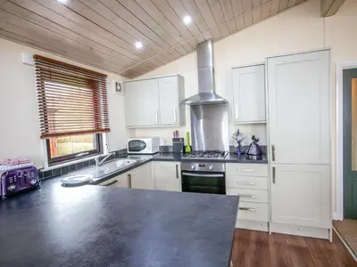 a kitchen with white cabinets and a stove top oven at Chalet Loch Leven Lodge by Interhome in Ballingry
