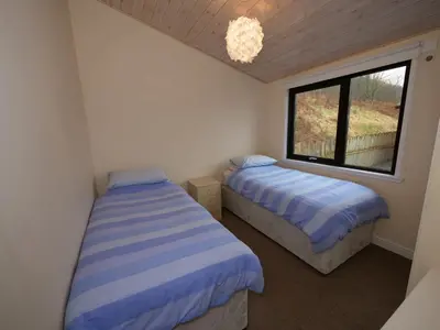 two beds in a small room with a window at Chalet Loch Leven Lodge by Interhome in Ballingry