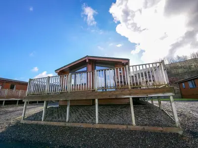a large wooden house with a large deck at Chalet Loch Leven Lodge by Interhome in Ballingry
