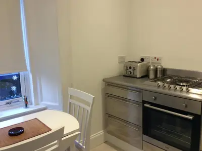 a kitchen with a stove and a table and a table and a chair at West Highland Way Rooms ED30002F in Milngavie