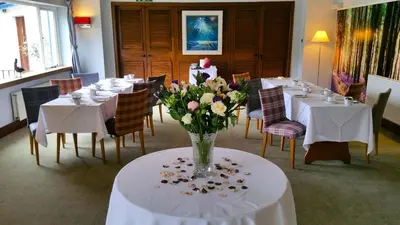 a dining room with white tables and a vase of flowers at The Four Seasons Hotel in Saint Fillans