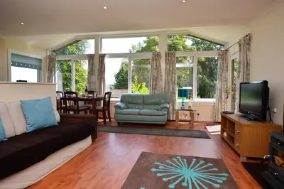 a living room with a couch and a television at Amber Lodge in Hunters Quay