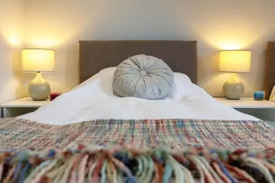 a bed with a pillow on it with two lamps at Lomond Serviced Apartments- Inglewood in Alloa