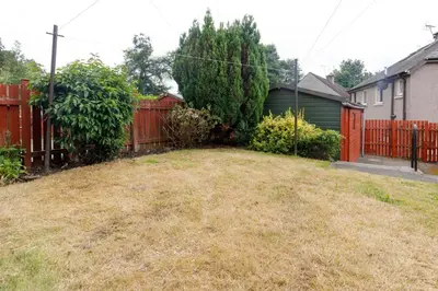 a backyard with a red fence and a yard at Lomond Serviced Apartments- Inglewood in Alloa