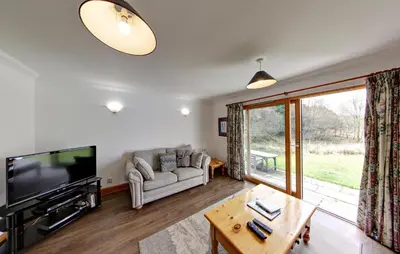 a living room with a couch and a tv at Stob Binnein Cottage in Crianlarich