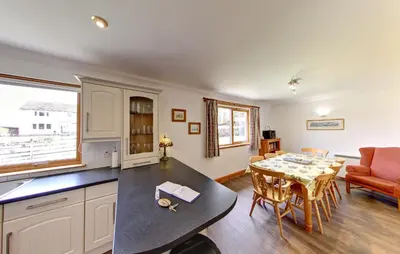a kitchen and dining room with a table and a dining room at Stob Binnein Cottage in Crianlarich
