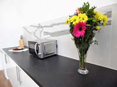 a vase of flowers on a counter next to a microwave at Signature - Langlands House in Glasgow