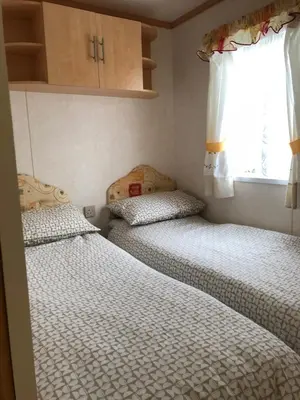 two beds in a small room with a window at 57 Glenfinart Caravan Park in Ardentinny