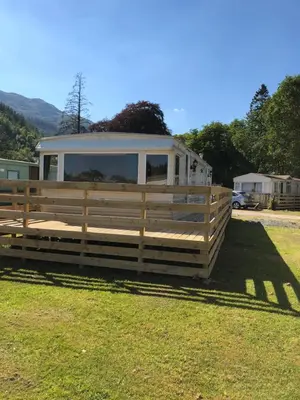 a trailer in a field with a fence at 57 Glenfinart Caravan Park in Ardentinny