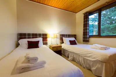 a bedroom with two beds with towels on them at Eagle Lodge with stunning loch and mountain view in Crianlarich