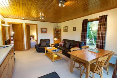 a living room with a couch and a table at Eagle Lodge with stunning loch and mountain view in Crianlarich