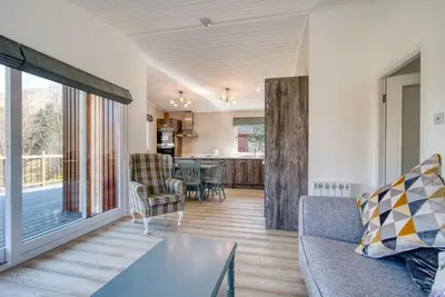 a living room with a couch and a table at Gamekeeper Lodge loch and mountain view free wifi in Crianlarich
