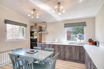 a kitchen with a table and chairs and a counter at Gamekeeper Lodge loch and mountain view free wifi in Crianlarich