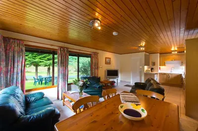 a living room with a wooden ceiling and a table at Kestrel Lodge with mountain view free wifi in Crianlarich