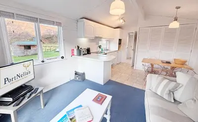 a living room with a couch and a kitchen at Lapwing Lodge with loch and mountain view in Crianlarich