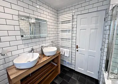 a bathroom with two sinks and a mirror at Lapwing Lodge with loch and mountain view in Crianlarich