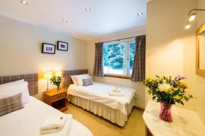 a hotel room with two beds and a window at Osprey Lodge with river and mountain view in Crianlarich